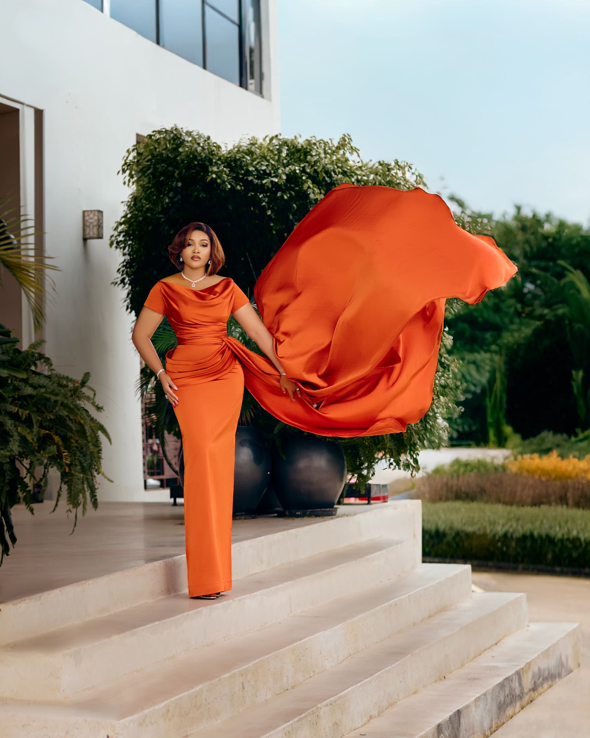 Udemé Atelier — the EMBER GOWN in burnt-orange satin, train caught mid-motion